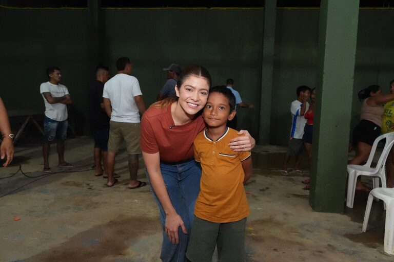Aryel Almeida abraçada com um menino, os dois sorrindo, em encontro com moradores de Lábrea