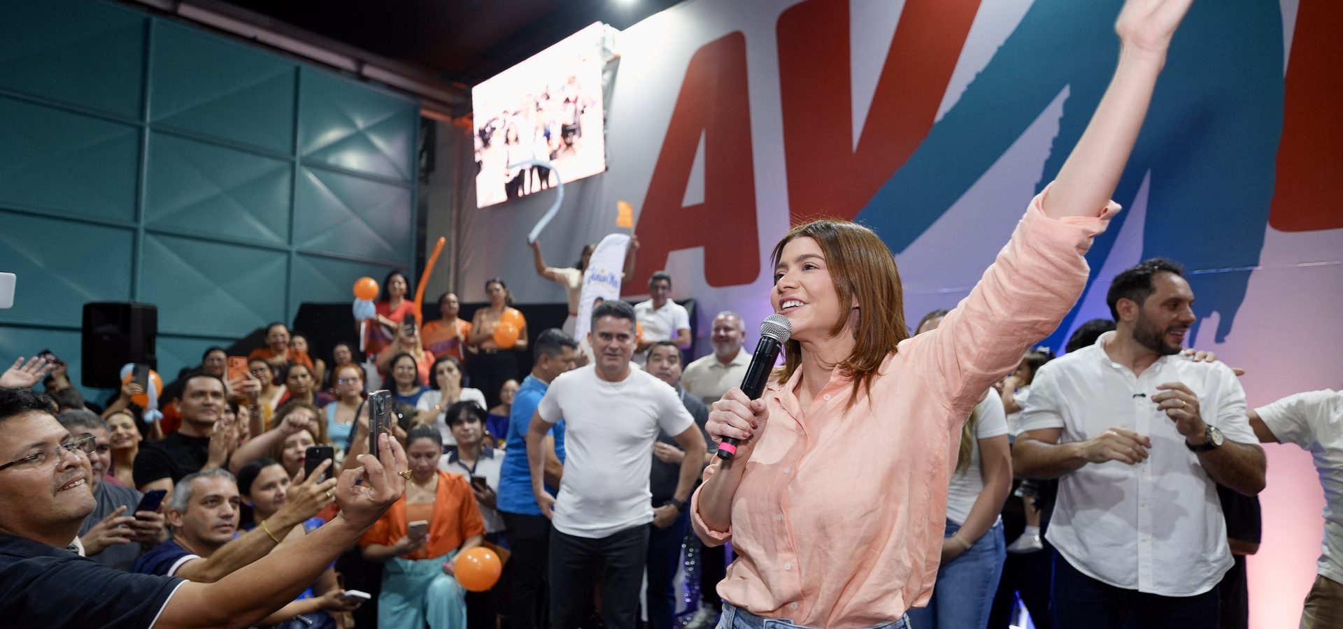 Aryel Almeida ao microfone, de braço erguido, em ato público diante de apoiadores